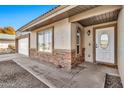 A close up of the house featuring an entrance showing a decorative window and a beige rock border at 1565 W Plana Ave, Mesa, AZ 85202