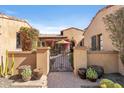 Inviting gated courtyard entrance with blooming bougainvillea and decorative potted cacti at 18683 N 101St Pl, Scottsdale, AZ 85255