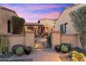 View of a private courtyard with a wrought iron gate, desert landscaping, and stylish outdoor decor at 18683 N 101St Pl, Scottsdale, AZ 85255