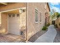 Side view of a townhome featuring an attached garage with stone accents and a narrow walkway at 2150 E Bell Rd # 1134, Phoenix, AZ 85022