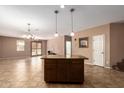 Open-concept kitchen featuring tile floors, a center island, modern lighting and neutral-colored walls at 3127 W Apollo Rd, Phoenix, AZ 85041