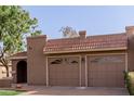 This home features a charming brown two-car garage with decorative windows and a red tile roof at 9837 E Michigan Ave, Sun Lakes, AZ 85248