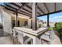 Outdoor kitchen with bar seating and a pergola, perfect for entertaining at 10145 E Cintron Dr, Mesa, AZ 85212