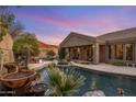 Backyard pool with waterfall feature, lush landscaping, covered patio, and mountain views at 10886 E Ludlow Dr, Scottsdale, AZ 85255