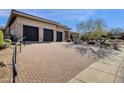 Wide brick driveway with a three-car garage and desert landscaping at 13827 N Sunset Dr, Fountain Hills, AZ 85268