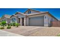 Attractive single-story house featuring desert landscaping, complemented by a brick driveway and a neutral color scheme at 15262 W Garfield St, Goodyear, AZ 85338