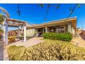 Backyard view featuring a covered patio, grassy area, lush landscaping and outdoor pergola at 18635 W Miami St, Goodyear, AZ 85338