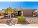 Charming home with manicured landscaping, a paver driveway, and an American flag on a clear, blue-sky day at 18635 W Miami St, Goodyear, AZ 85338