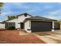 Exterior home view featuring a black trimmed roof, desert landscaping and a black garage door at 18829 N 15Th Pl, Phoenix, AZ 85024