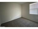 A well-lit bedroom with plush carpeting and a window offering natural light at 36638 W Santa Clara Ave, Maricopa, AZ 85138