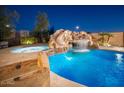 Backyard pool area with stone features, slide, waterfall, and lush landscaping at 7157 E Ivyglen Cir, Mesa, AZ 85207
