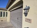 Attached two-car garage featuring a gray door with a stone address marker at 7576 W Quail Ave, Glendale, AZ 85308