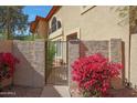 Condo exterior showcasing a private gate, desert landscaping with bougainvillea, and stucco walls at 10224 N 12Th Pl # 1, Phoenix, AZ 85020