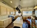 Well-lit kitchen boasts a center island, pot rack, and a dining table, creating a warm, inviting space at 1339 N Tucana Ln, Gilbert, AZ 85234