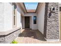 Close-up view of the front door with stone masonry accent siding and tile paver walkway at 14194 W Sand Hills Rd, Surprise, AZ 85387
