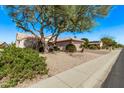 Inviting desert home with mature landscaping, tile roof, and a spacious three-car garage, creating great curb appeal at 18155 N Sterling Dr, Surprise, AZ 85374