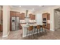 Modern kitchen features an island with bar seating, stainless steel appliances, and tile backsplash at 20584 W Hillcrest Blvd, Buckeye, AZ 85396