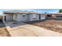 Single story grey home featuring an attached carport, lush yard and cracked driveway at 3821 W Verde Ln, Phoenix, AZ 85019