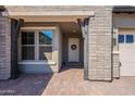 Inviting front porch with brick accents, supporting columns, and a charming wreath on the entrance door at 9960 E Strobe Ave, Mesa, AZ 85212