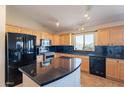 Well-lit kitchen with black appliances, a black countertop island, and light wood cabinetry at 10368 E Gold Nugget Ct, Gold Canyon, AZ 85118