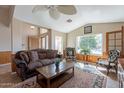 Cozy living room featuring tile floors, a decorative ceiling fan, wood paneling, and large windows providing natural light at 10368 E Gold Nugget Ct, Gold Canyon, AZ 85118