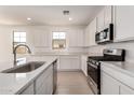 Bright kitchen with white cabinets, quartz countertops, stainless steel appliances and wood-look tile floors at 12361 W Marguerite Ave, Avondale, AZ 85323