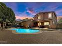 Beautifully lit backyard featuring a private pool and covered patio, ideal for evening relaxation at 15260 W Alexandria Way, Surprise, AZ 85379