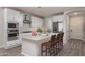 Bright kitchen featuring white cabinets, stainless steel appliances, and a center island with chairs at 16277 W Mariposa Grande --, Surprise, AZ 85387