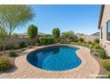 Sparkling pool with a brick surround and lush landscaping in a private backyard setting at 18369 W La Senda Dr, Surprise, AZ 85387