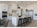 Spacious white kitchen featuring a large island with seating, modern appliances, and stylish pendant lighting at 20255 W Highland Ave, Litchfield Park, AZ 85340