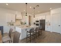 Bright kitchen with white cabinets, a large island, pendant lighting, and stainless steel appliances at 20277 W Highland Ave, Litchfield Park, AZ 85340
