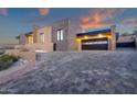 Modern home featuring an attached two-car garage, brick-paved driveway, and well manicured landscaping at 26885 N 87Th Dr, Peoria, AZ 85383