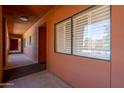 Hallway with view of a large window with closed shutters and tan paint at 4303 E Cactus Rd # 308B, Phoenix, AZ 85032
