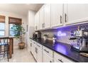 Stylish kitchen with white cabinets, black countertops, and a backsplash, creating a modern design at 8362 W Rosewood Ln, Peoria, AZ 85383