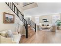 Bright living room with light wood floors, shutters, and staircase with black railing at 10917 E Raintree Dr, Scottsdale, AZ 85255