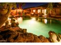 Backyard pool at night with lush tropical landscaping and a cozy fire pit under the covered patio at 11182 S Hopi Dr, Goodyear, AZ 85338