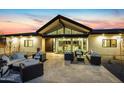 The rear of the home has an expansive patio area with elegant outdoor seating beneath a gabled roof extension at 12201 N 65Th St, Scottsdale, AZ 85254