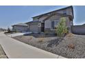 Well-maintained front exterior featuring desert landscaping, neutral stucco, and a long driveway at 16873 W Fetlock Trl, Surprise, AZ 85387