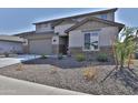 Suburban two-story home with desert landscaping, stone accents, a two-car garage and neutral stucco at 16873 W Fetlock Trl, Surprise, AZ 85387