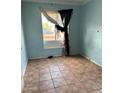Bedroom featuring tile flooring, a bright window with hanging curtains, and blue painted walls at 2912 E Monroe St, Phoenix, AZ 85034