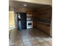 Functional kitchen featuring tiled walls, wooden cabinets, and modern black and white appliances at 2912 E Monroe St, Phoenix, AZ 85034