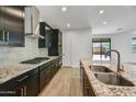 Contemporary kitchen featuring granite counters, stainless steel appliances, dark cabinetry, and tile backsplash at 31783 N 130Th Ave, Peoria, AZ 85383