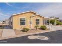 Well-kept single-story home with lovely landscaping and covered carport, painted in light yellow at 40569 N Wedge Dr, San Tan Valley, AZ 85140