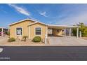 Inviting single-story home with covered carport, lush landscaping, and painted in light yellow at 40569 N Wedge Dr, San Tan Valley, AZ 85140