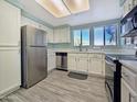 Stylish kitchen with stainless steel appliances, white cabinets, and gray wood-look floors at 750 E Northern Ave # 2088, Phoenix, AZ 85020