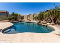 Sparkling backyard pool featuring rock waterfall, lush landscaping, and ample space for entertaining at 11318 S Hopi Dr, Goodyear, AZ 85338