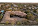 Aerial view of a custom home with a unique roof design nestled amongst desert landscape and community at 11988 E Larkspur Dr, Scottsdale, AZ 85259