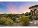 Picturesque backyard featuring a fire pit, stone accents, desert landscaping, and stunning mountain views at 11988 E Larkspur Dr, Scottsdale, AZ 85259