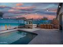 This backyard has a pool, hot tub, and outdoor bar under cafe lights with mural-covered walls at 1700 W Paisley Dr, San Tan Valley, AZ 85144