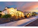 Charming single-story home exterior with tiled roof, neutral stucco, tasteful front landscaping, and warm accent lighting at 18322 W Thistle Landing Dr, Goodyear, AZ 85338